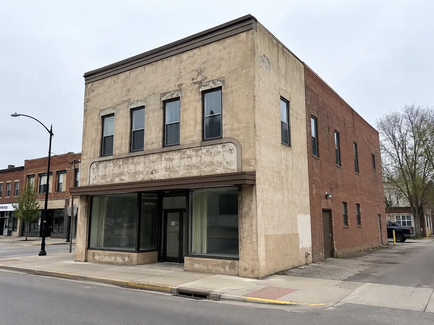 Existing corner commercial building on a quiet street before exterior redesign.